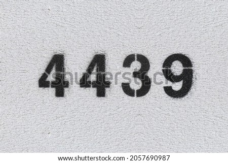 Black Number 4439 on the white wall. Spray paint. Number four thousand four hundred thirty nine.