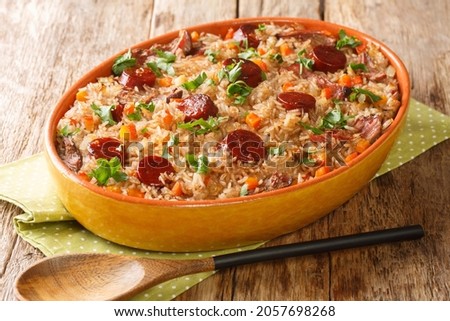 Authentic Arroz de pato duck rice is a traditional recipe from Portugal cooked with red wine, onion, carrot and chorizo close up in the baking dish on the wooden table. Horizontal
 Royalty-Free Stock Photo #2057698268