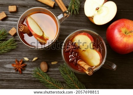 Aromatic hot mulled cider on black wooden table, flat lay