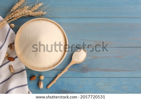 Uncooked organic semolina, spikelets and nuts on light blue wooden table, flat lay. Space for text Royalty-Free Stock Photo #2057720531