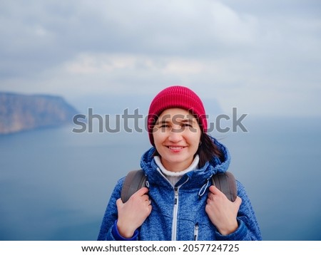 Back view of woman in blue jacket and hat on shore of North sea on cold winter day. Mood Scandinavian weather. travel adventure lifestyle idea and concept
