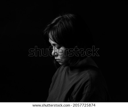 Side view portrait of sad woman, looking down, black background, black and white image. Royalty-Free Stock Photo #2057725874
