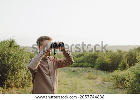 The man looks through binoculars. Hunting and travel concept.