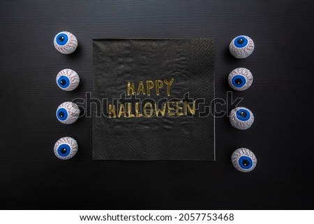 Funny Halloween treat - Candy eyeballs with a Napkin written "Happy Halloween" on dark background. Copy space Royalty-Free Stock Photo #2057753468