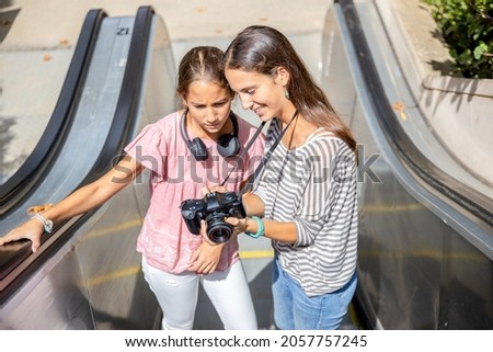 Girls looking at photos in their camera on the escalator
