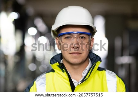 Professional Confident Serious Engineer Looking at Camera, Wearing Safety Uniform and Goggles Standing at Heavy Industry Factory Ready to Manufacturing Works During Metal Welding by Staff Royalty-Free Stock Photo #2057757515