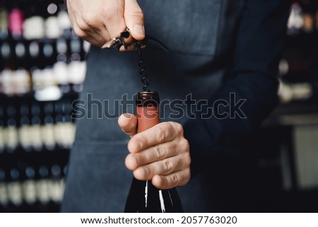 Sommelier opens cork of bottle of red wine with corkscrew. Royalty-Free Stock Photo #2057763020