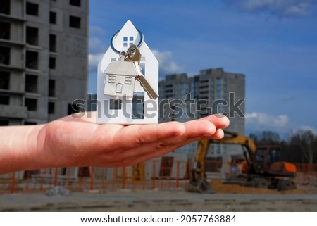 Man holds the keys to the house in his hands against the background of a multi-storey building. Concept for buying and renting apartments