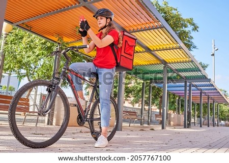 A cyclist delivery woman checks the order address on her smartphone