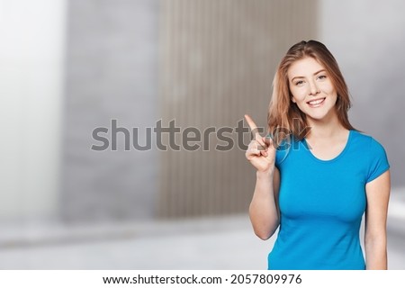 Joyful lady pointing at blank space, in excitement over background.