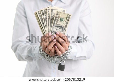 Women hands tied with chain hold one hundred dollar bills