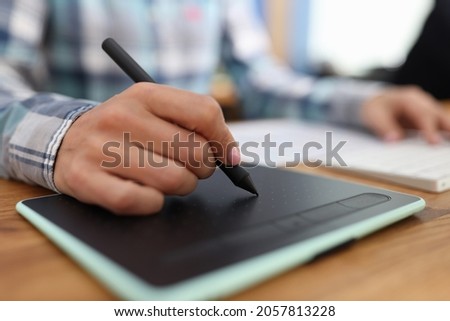 Graphic editor retouching drawings on graphic tablet in studio