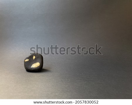 Funny face in gold on black stone on a dark background. The concept of human emotions, moods, anxiety, discontent, fear, apprehension, experience, annoyance. Bad or good mood