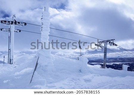 Frozen under strong cold wind snow, ski lift at mountain top, close up photo of ski resort lift equipment