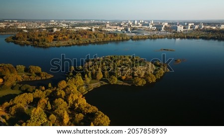 Flight over the autumn park. Trees with yellow autumn leaves are visible. On the horizon there is a blue sky and city houses. The park lake is visible. Aerial photography.