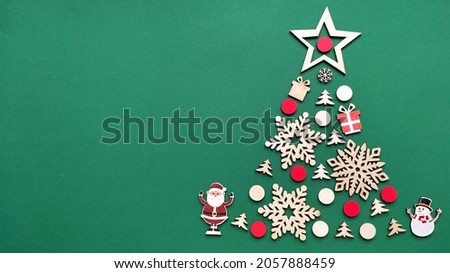 Christmas tree made from winter wooden elements on a green background. Wood snowflakes, fir trees, gifts. Vertical orientation. Space for text.