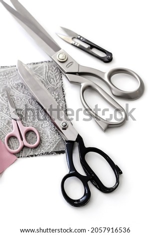 Tailor's scissors are lying on the table, next to scraps of fabric. Space for text. Concept: atelier, cutting and sewing courses, needlework, custom tailoring, hardware store.