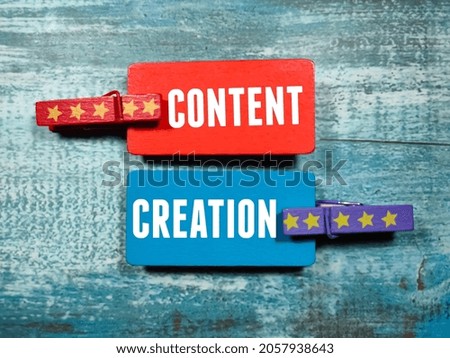 Colored wooden board and wooden clips with the words content creation on a wooden background.