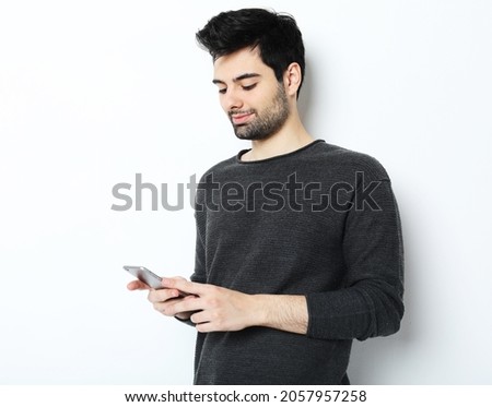 tehnology, emotion and people concept: Smiling young man talking by smartphone, close up