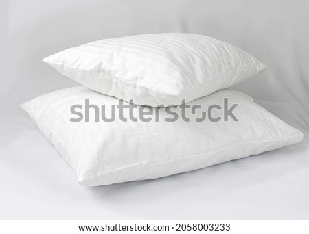 Two white pillows in striped cotton pillowcases. Satin jacquard bedding and accessories. Air soft pillows filled with swan down and bamboo Royalty-Free Stock Photo #2058003233