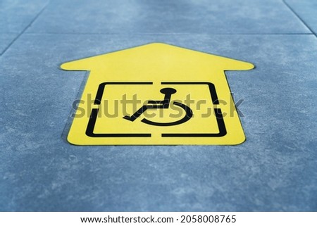 A drawing of a wheelchair on a yellow arrow glued to the tile in the waiting room. Sign Direction of movement