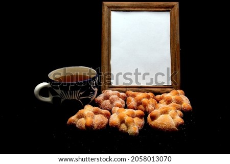 Fluffy and sugary bread of the dead in an offering for the Day of All Saints and All Saints in November in Mexico with coffee, candles and picture frames with the image of the deceased relative
