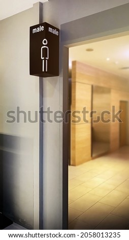 Male public toilet sign at the entrance with shallow dof blurred background inside the toilets