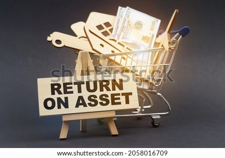 Business and finance concept. On a black background, there is a shopping cart with purchases, next to an easel and a sign with the inscription - RETURN ON ASSET