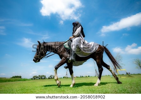 Portrait of Muslim woman and horse in the meadow