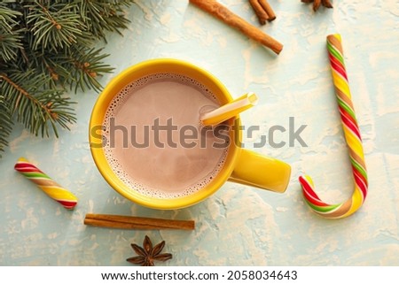 Cup of hot cocoa drink, fir branch and candy cane on color background