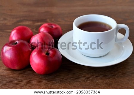 Autumn composition of red apples lying on wooden table and white cup of tea. Concept of home comfort and warmth. Hello, September!