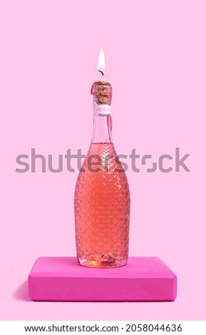 Unique bottle with lot of little hearts all around it. Candle light on the top of bottle. Rose drink and pink pedestal under. Baby pink background.