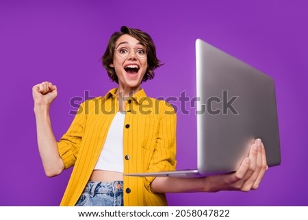 Portrait of attractive cheerful lucky skilled girl using laptop rejoicing isolated over bright violet purple color background