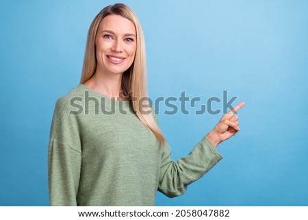 Photo of young beautiful woman indicate finger empty space advertise recommendation isolated over blue color background