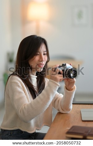Charming asian young female taking photo by vintage retro camera in modern coffee shop. leisure and hobby concept.