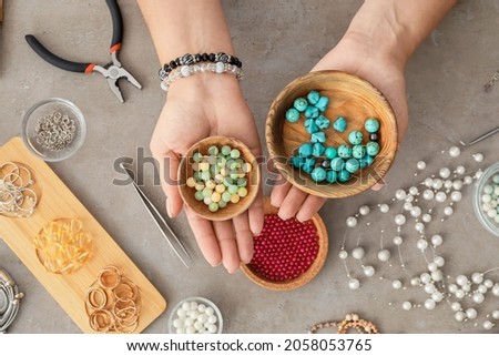 Female jewelry designer with beads  on gray background