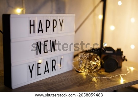 lightbox with happy new year text on the table or shelf with vintage camera and led lights