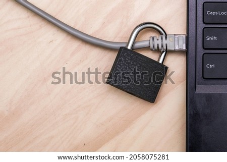 padlock on an internet cable connected to a laptop concept data protection cybersecurity. High quality photo