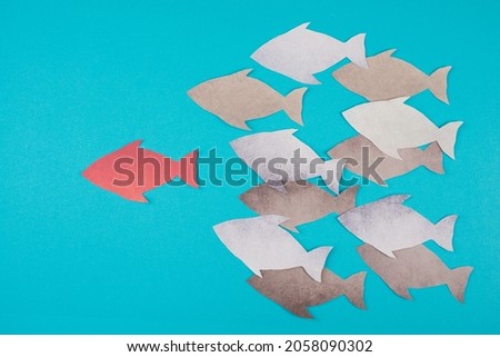 Red fish is the leader of the group, paper cut, blue colored background Royalty-Free Stock Photo #2058090302