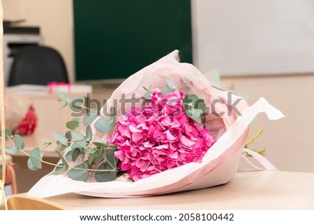 A bouquet of beautiful bright flowers on a school desk on September 1 against the background of a school board. Selective focus. Close-up