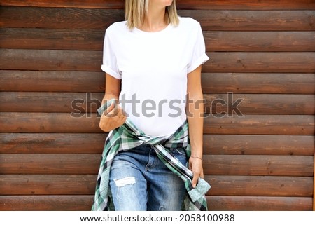 Girl wearing blank white t shirt and denim ,green plaid shirt on wooden background. mockup for t shirt printing store mock up Royalty-Free Stock Photo #2058100988