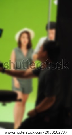 Blurry images of making TV commercial movie video in big green screen background. Film crew team working with actor. Recording by professional digital camera and lighting set. film behind the scenes
