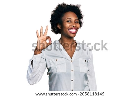 African american woman with afro hair wearing casual white t shirt smiling positive doing ok sign with hand and fingers. successful expression. 