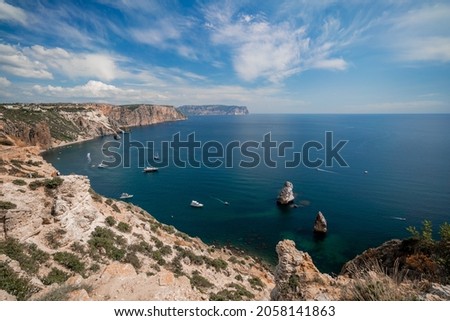 Two rocks stick out of the water in the middle of the turquoise sea. Scenic ocean view. Speed boat sails on the sea. High quality photo