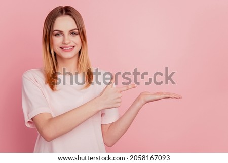 Photo of positive blonde promoter lady direct finger hand demonstrate empty space sale option on pink background