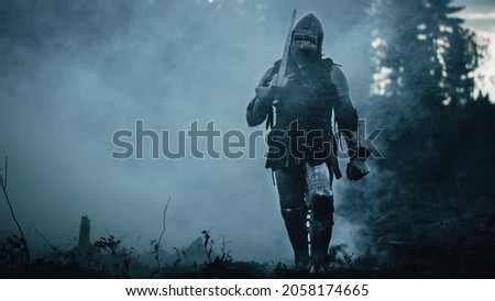 Lonesome Medieval Warrior Marching Through Forest. Last Surviving Crusader, Soldier, Knight Wearing Full Body Armor, Helmet, Shield and Sword Traveling Through Mysterious Land He Invaded to Colonise Royalty-Free Stock Photo #2058174665