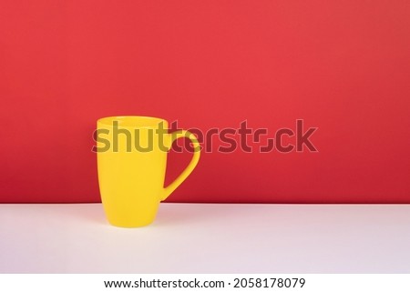 yellow cup on white table against red wall background