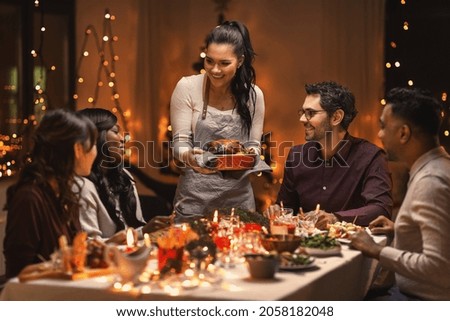 holidays and celebration concept - multiethnic group of happy friends having christmas dinner at home Royalty-Free Stock Photo #2058182048