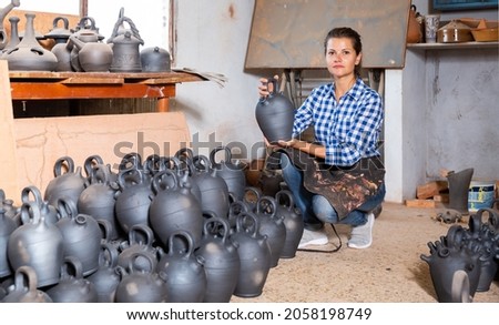 Female artisan in apron having ceramics in stock. High quality photo