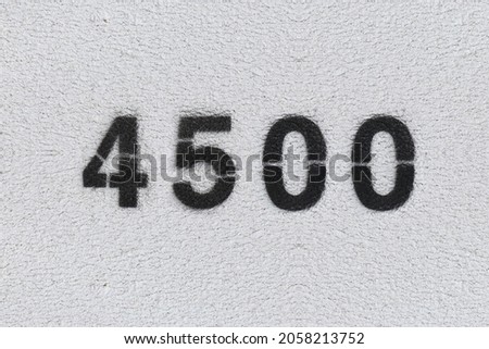Black Number 4500 on the white wall. Spray paint. Number four thousand five hundred.